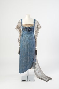 Vestido de noche de seda azul con mangas de red dorada y cola bordada en tiras de metal dorado y decorada con gemas azules y borlas, 1911